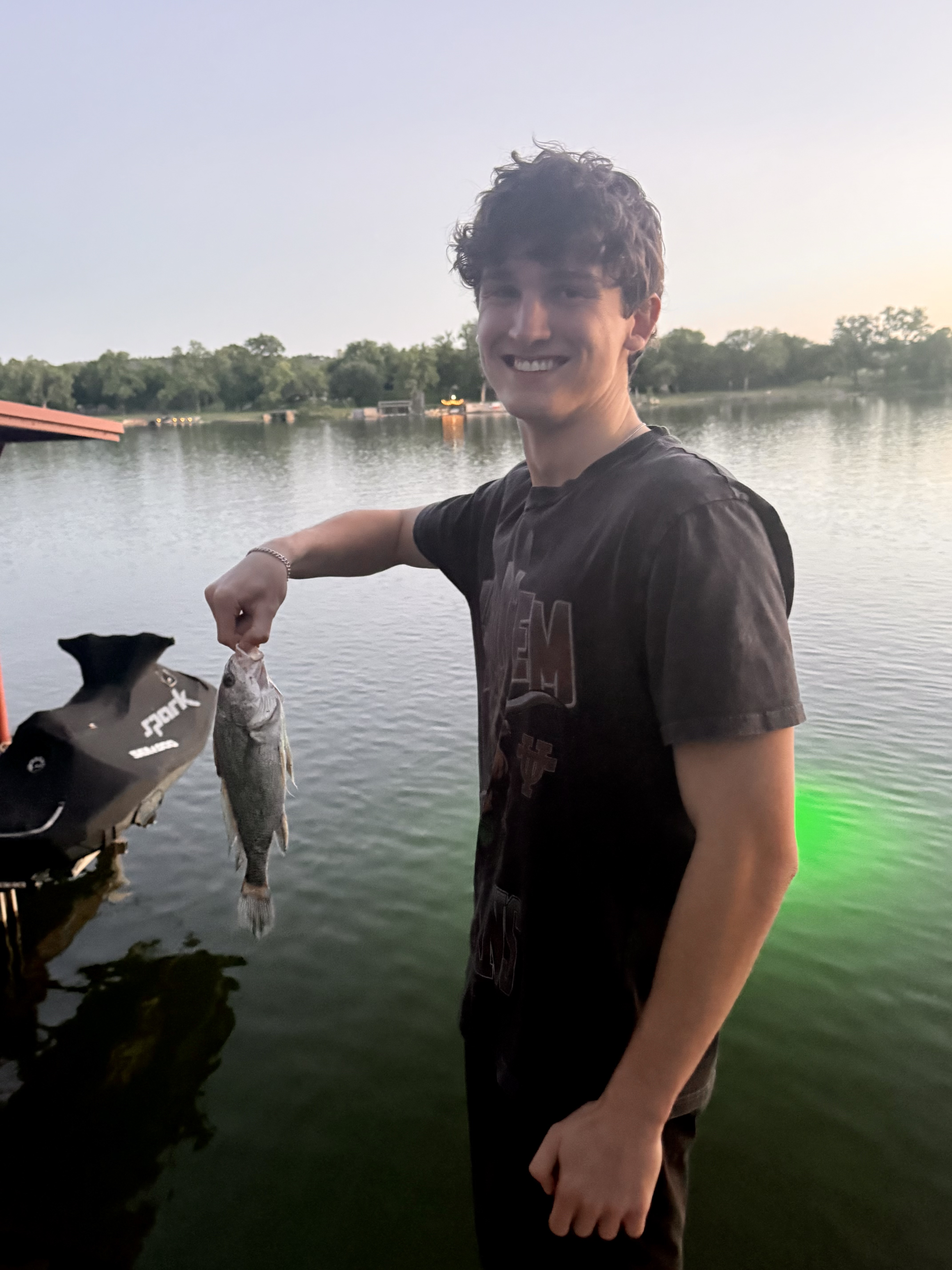 Garrett Goggans holding a fish by the lake